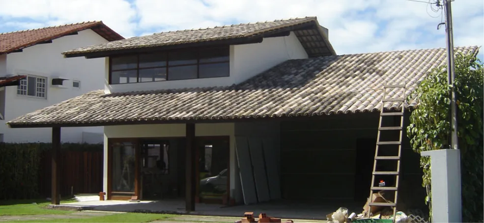 Casa com o telhado encardido e esverdeado.